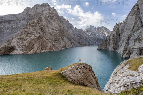 Tourist at the blue mountain lake between rocky steep mountain peaks, Kol Suu Lake, Sary Beles