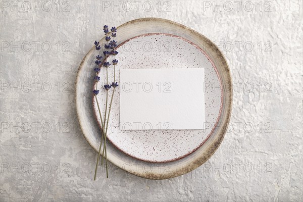 White paper invitation card, mockup with lavender on ceramic plate and gray concrete background.