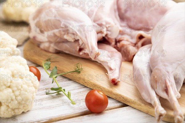 Whole raw rabbit with cauliflower, tomatoes and spices on a white wooden background and linen
