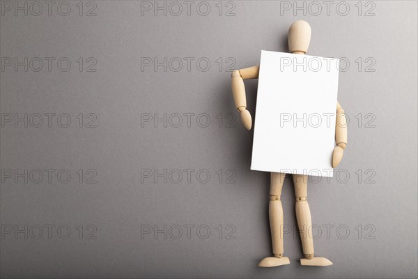 Wooden mannequin holding blank poster on gray pastel background. copy space, isolated, presentation