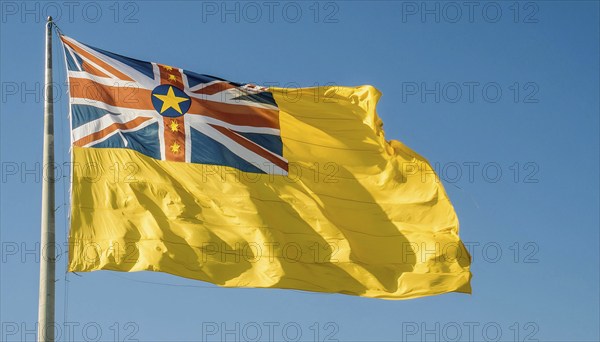 The flag of Niue, an island state in the Pacific Ocean, flutters in the wind, isolated against a