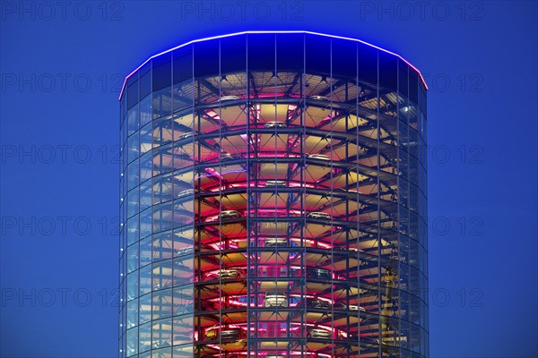 An illuminated car tower with new cars for delivery in the evening, Autostadt, Volkswagen AG,