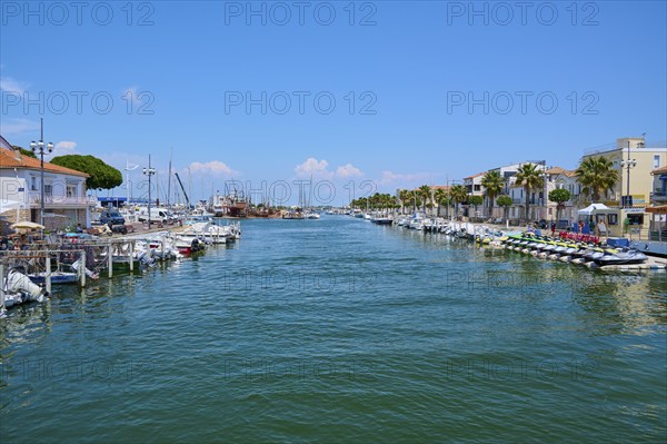 Coastal town with colourful houses and palm trees, boats in the water, on a sunny day, summer, Le