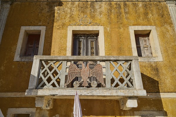 Traditional building with balcony and eagle motif, characterised by yellow colour, Colourful