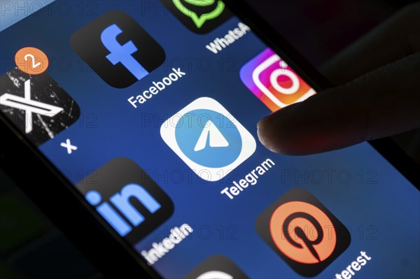 The social media Telegram messenger logo is being displayed on a smartphone screen and on a