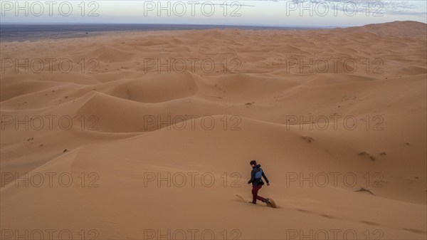 Woman walking over dunes, Erg Chebbi, Sahara, Merzouga, Morocco, Africa