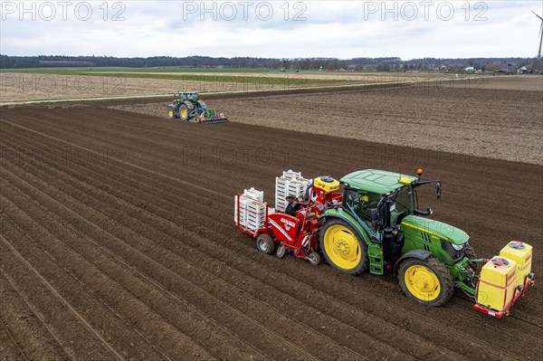 Early potatoes are laid in the soil of the field with a planting machine, tractor with roundabout