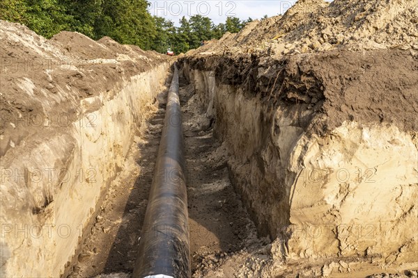 Laying of district heating pipes, next to a field, with maize, the district heating comes from a