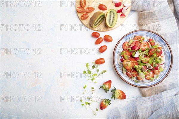 Vegetarian fruits and vegetables salad of strawberry, kiwi, tomatoes, microgreen sprouts on white