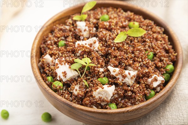 Quinoa porridge with green pea and chicken in wooden bowl on a white wooden background and linen