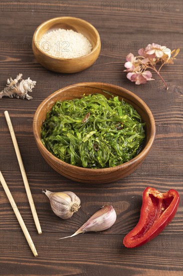 Chuka seaweed salad in wooden bowl on brown wooden background. Side view, close up
