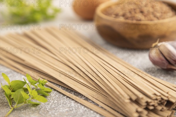 Japanese buckwheat soba noodles with tomato, eggs, spices, herbs on brown concrete background. Side