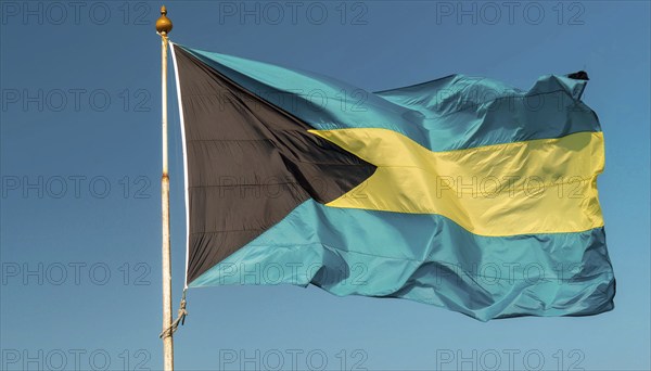 The flag of the Bahamas flutters in the wind, isolated against a blue sky