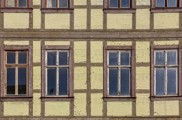 Façade of a historic half-timbered building with yellow walls and several rectangular windows with