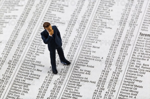 A small figure and the prices of shares in a newspaper. Making money on the stock market. Profits