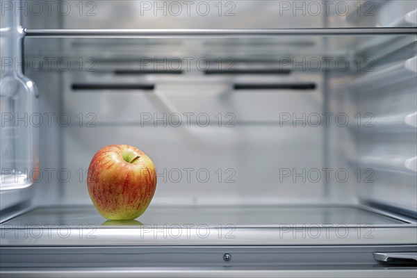 Open refrigerator with only one single apple inside. KI generiert, generiert, AI generated