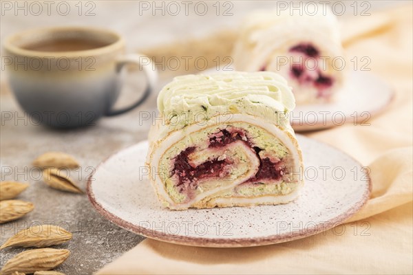 Roll biscuit cake with cream cheese and jam, cup of coffee on brown concrete background and orange