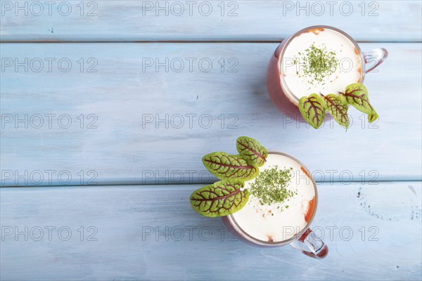 Tomato juice with sorrel and sour cream in glass on blue wooden background. Healthy drink concept.