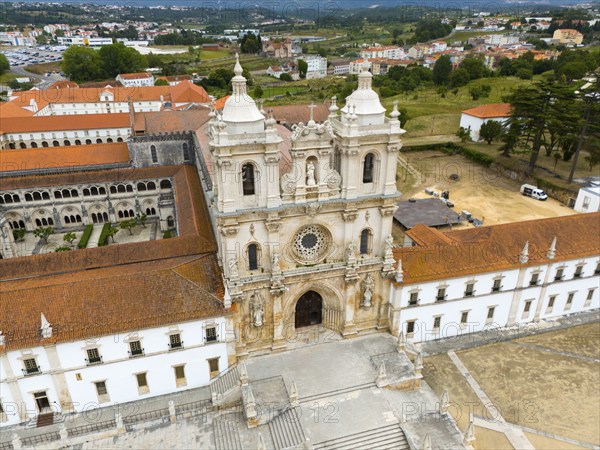 The picture shows a historic monastery with baroque architecture in an urban landscape, aerial