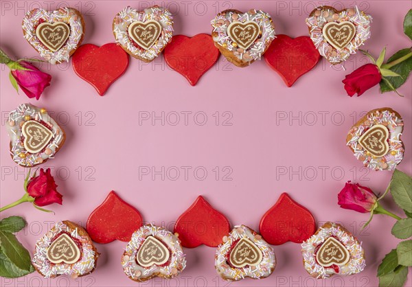 Frame made of heart-shaped cupcakes, red hearts and roses, Valentine's Day, pink background