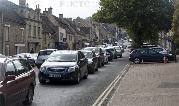 Tourist honeypot village street crowded with traffic in Burford, Oxfordshire, England, UK