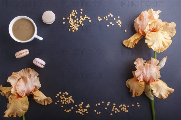Orange iris flowers and a cup of coffee on a black background. Morninig, spring, fashion