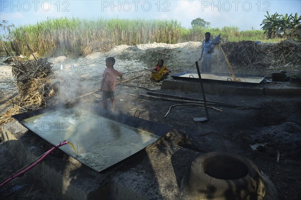 Workers boiling sugarcane juice as they are making Gur (jaggery) in a village on December 10, 2021
