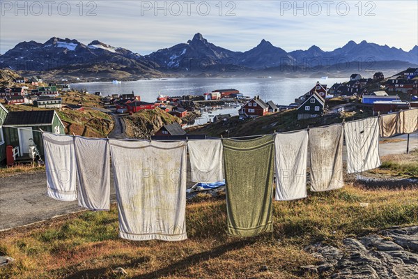 Laundry drying on clothesline in Inuit settlement, houses on a fjord with steep mountains, autumn,