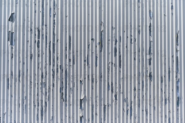 Weathered metal wall with peeling paint, showing industrial texture and vertical lines, Sandnes,