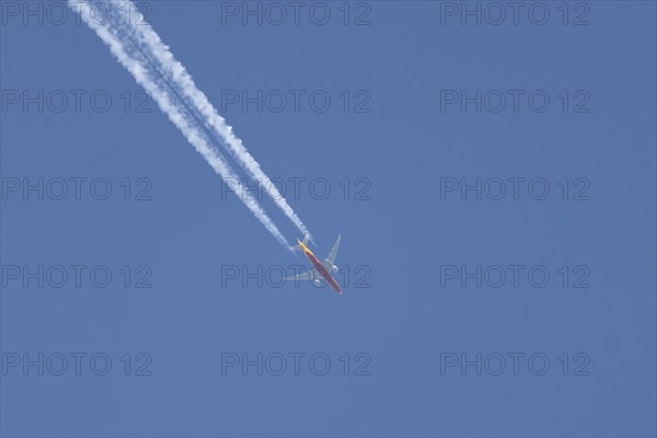 Boeing 767 jet cargo aircraft of DHL flying in a blue sky with a vapor trail or contrail behind,
