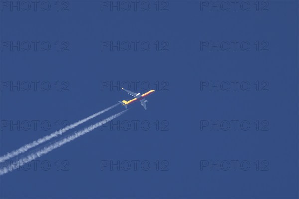 Boeing 767 jet cargo aircraft of DHL flying in a blue sky with vapor trails or contrails behind,
