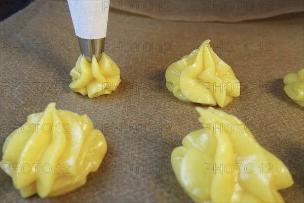 Swabian cuisine, preparation of mini cream puffs, press raw choux pastry through piping bag onto