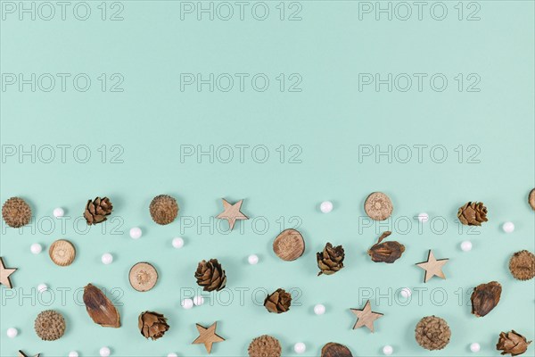 Seasonal decoration like wood slices and cones and Christmas star and snowball ornaments on mint