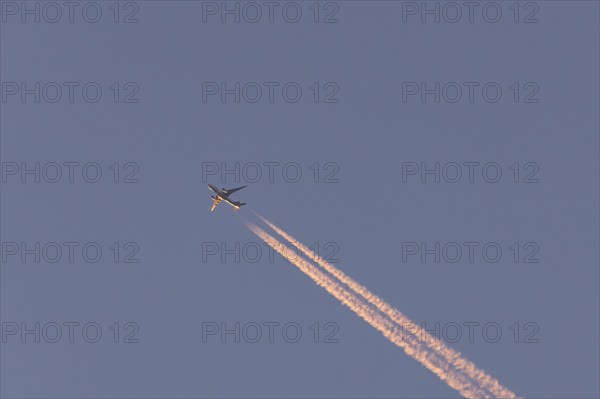 Boeing 767 jet cargo aircraft of FedEx flying in a blue sky with vapor trails or contrails behind,