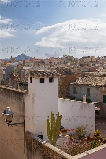 Mediterranean village with stone houses and green terraces under a slightly cloudy sky, Alcudia,