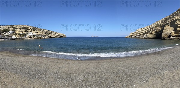 Panoramic photo of Matala bay front beach without beach chairs sunshades, Matala, Crete, Greece,