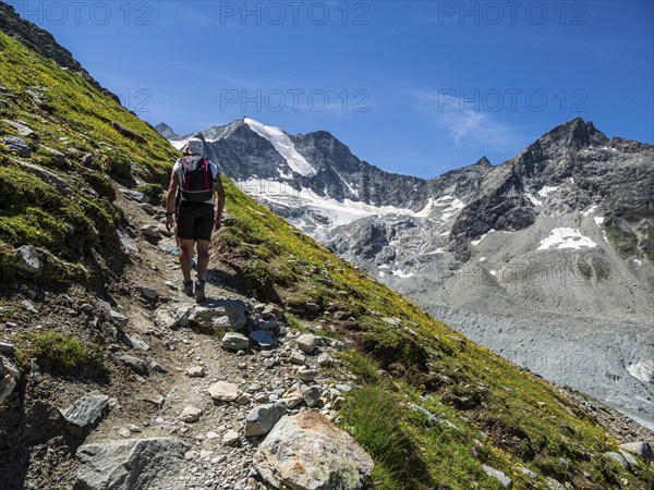 Hiking path up to mountain hut Cabane de Moiry, hiking tourists, Moiry glacier in the back, Valais,