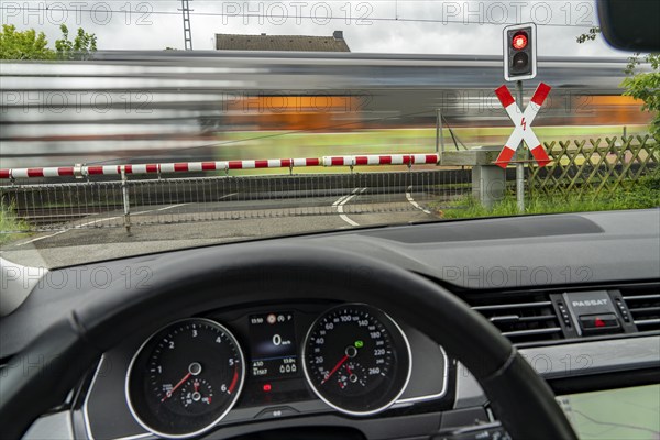 Car waiting at a level crossing, closed barriers, red warning light, traffic light and St Andrew's
