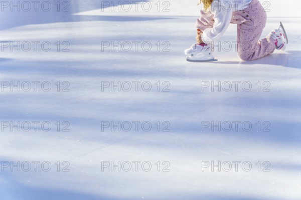 Girl lacing up her skates in an ice rink