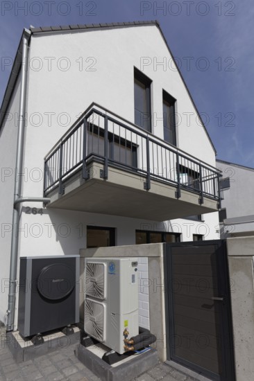 Outdoor units of an air-to-water heat pump in front of a newly built two-family house, heating and