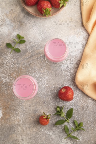 Sweet strawberry liqueur in glass on a gray concrete background and orange textile. top view, flat