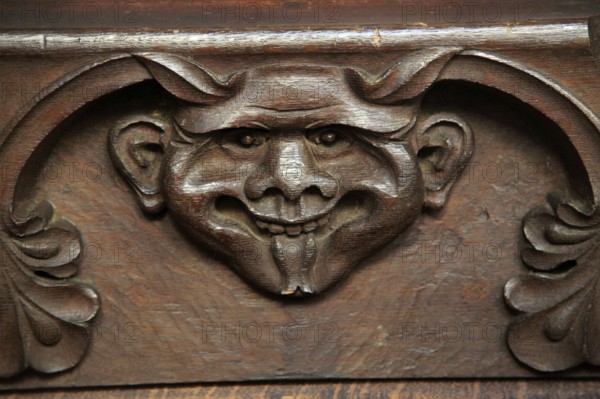Wooden carved devil face in bench seat, Ufford church, Suffolk, England, UK