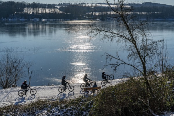 Winter in the Ruhr area, Lake Baldeney, snow-covered, partly frozen lake, walkers on the lakeside