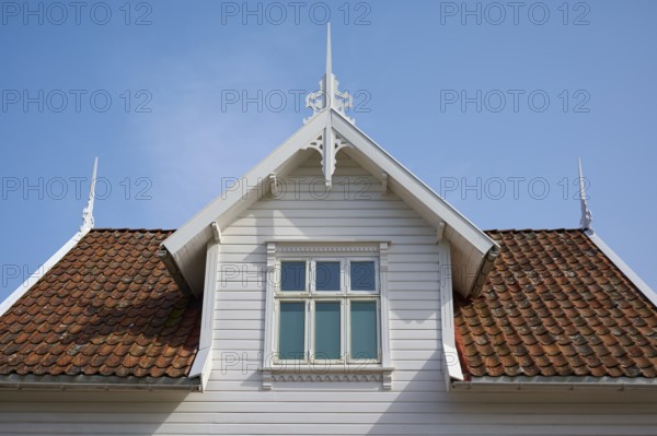 A traditional house with a red tiled roof and white wooden gable under a blue sky, Sandnes, Fylke