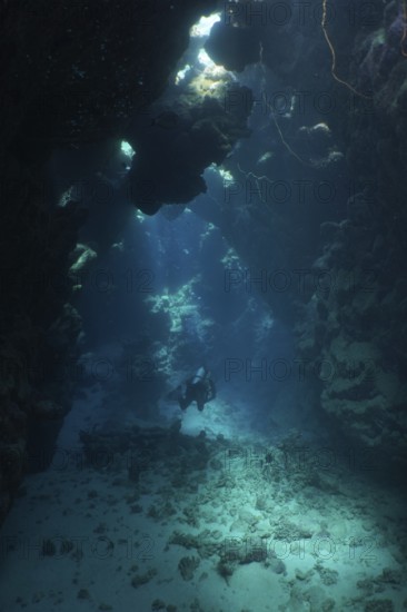 A lone diver in a dark underwater cave with rays of light, dive site Dangerous Reef, St Johns Reef,