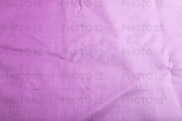 Fragment of smooth cotton purple tissue. Side view, natural textile background and texture