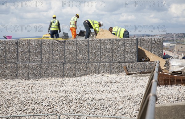 Repair work on steel mesh cages known as gabions which provide coastal defence at Chiswell, Isle of