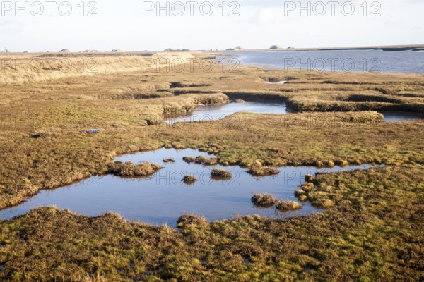 Saltmarsh in tidal creeks of the River Ore looking towards the military structures on Orford Ness,