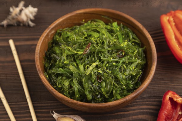 Chuka seaweed salad in wooden bowl on brown wooden background. Side view, close up, selective focus
