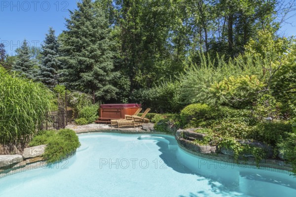 In-ground swimming pool surrounded by copper coloured wrought iron metal security fence and various